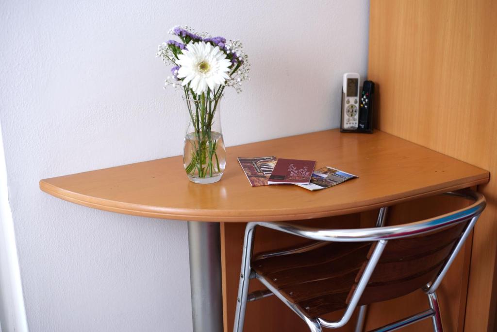 Stūrīša galds ar ziedu pušķi un tūrisma bukletiem, kas rada mājīgu un aicinošu atmosfēru.