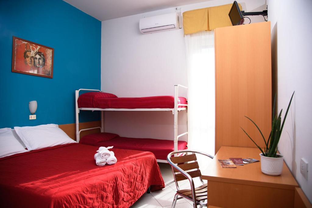 Sarkans gultas numurs ar diviem gultām un darba galdu, dekorēts ar zilu sienu un mākslas darbu. Numurā ir televizors un istabas augi, radot mājīgu atmosfēru.