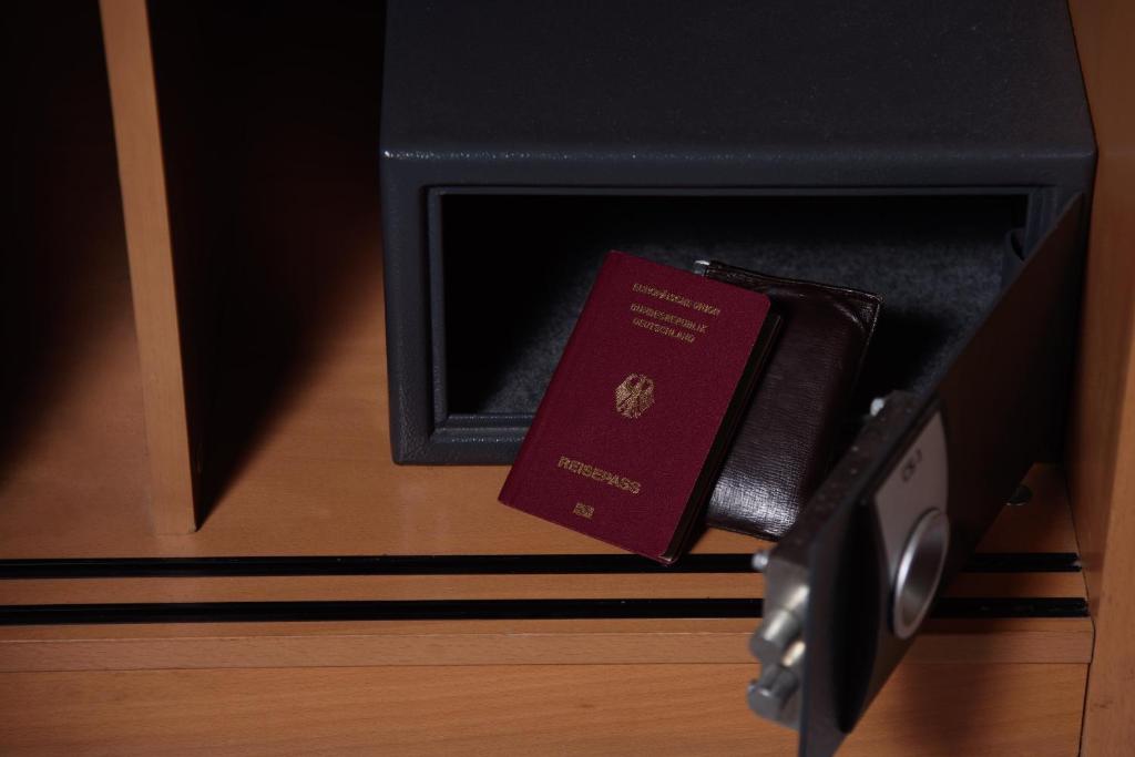 Sarkans pases vāks un melna maciņš, kas atrodas atvērtā seifā, kas ir novietots koka plauktā.