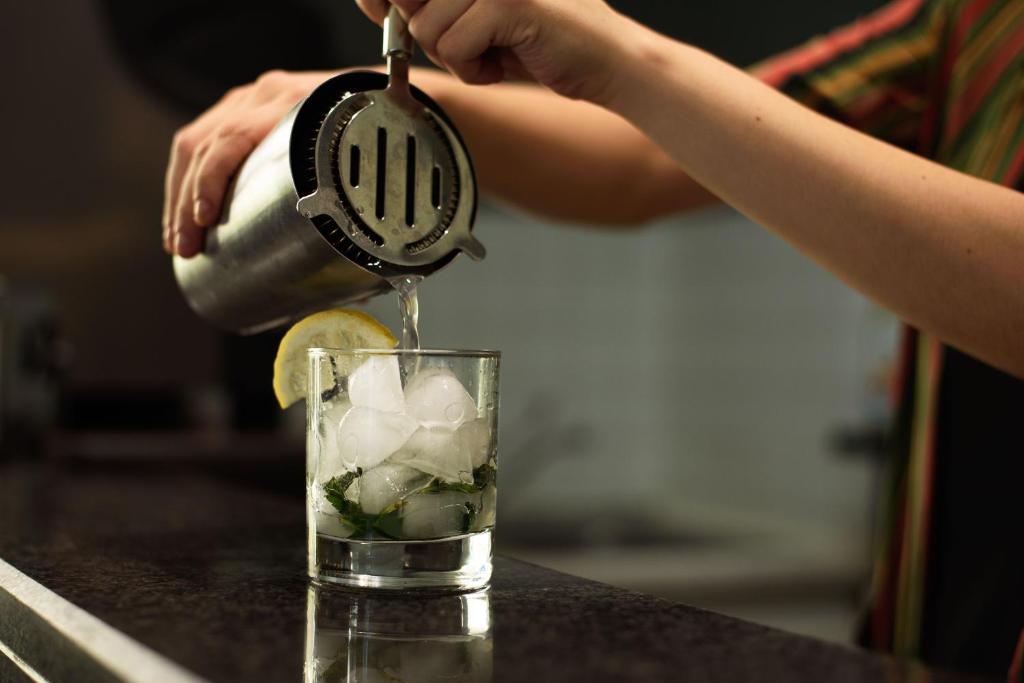 Kokteiļa pagatavošana ar ledu un svaigiem garšaugiem, kad dzēriens tiek kalts glāzē.