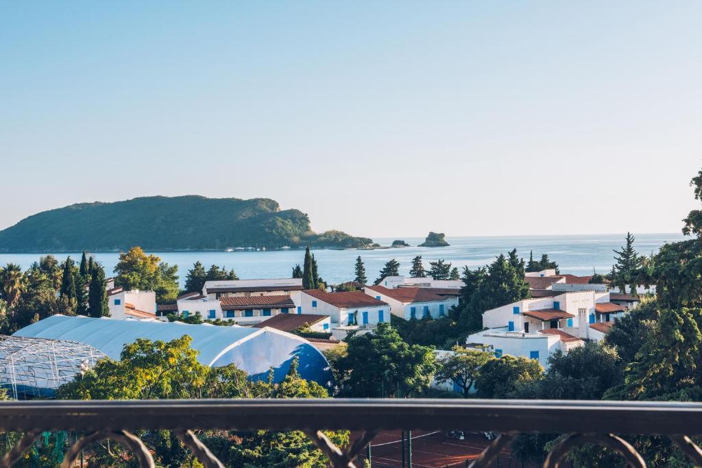 Skats uz piekrasti ar baltām mājām un zilu jūru, fons ar zaļiem kokiem un kalniem. Ideāla vieta atpūtai un relaksācijai.