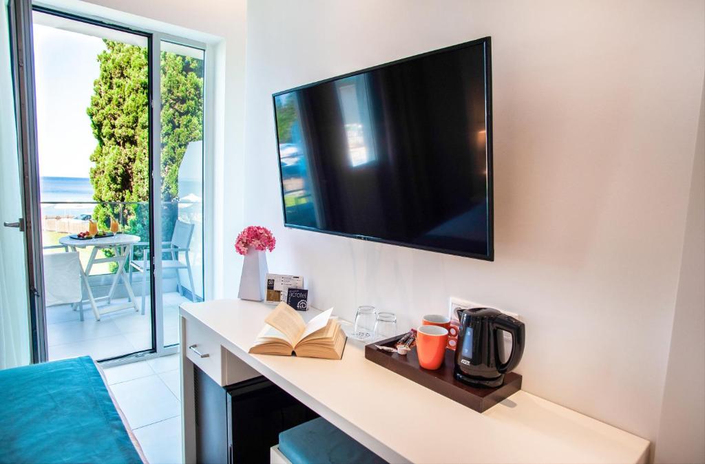 Mūsdienīgs viesnīcas numurs ar plakanā ekrāna televizoru, galdu un kafijas pagatavošanas iekārtu, kā arī piekļuvi balkona terasei ar skatu uz jūru.
