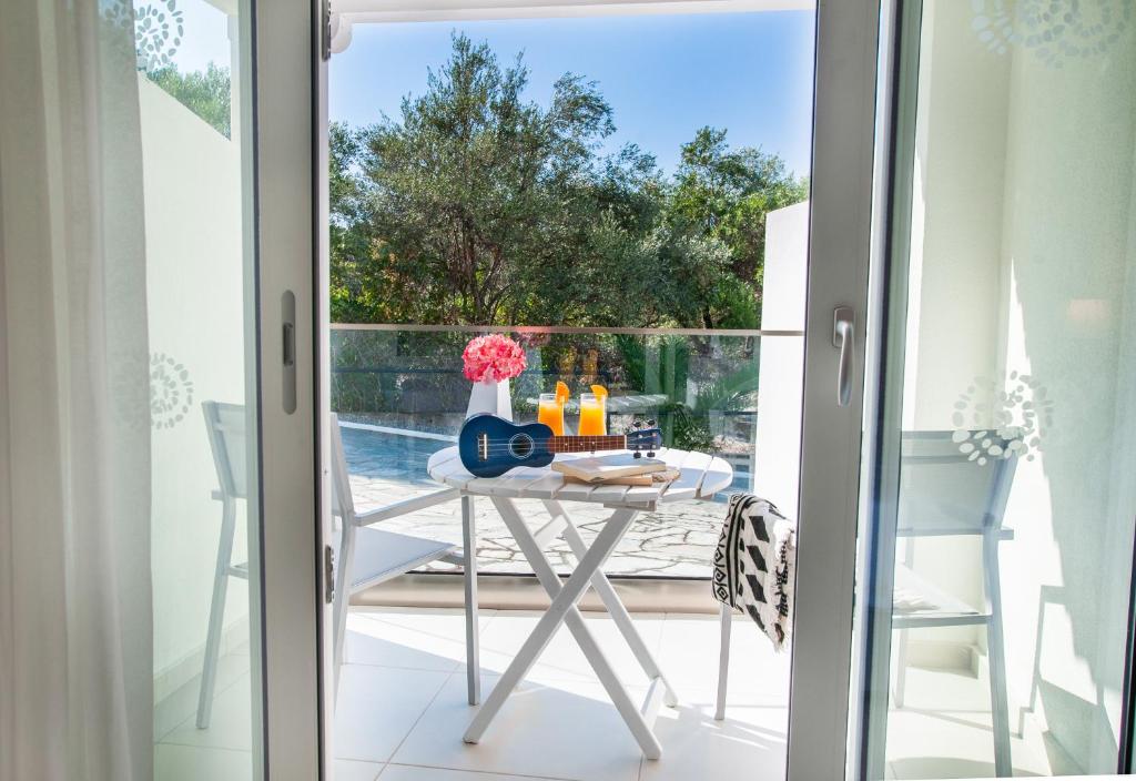 Saulaina terase ar galdu un krēsliem, uz galda novietots ukuleles, dzērieni un ziedi, skats uz baseinu un dabu.