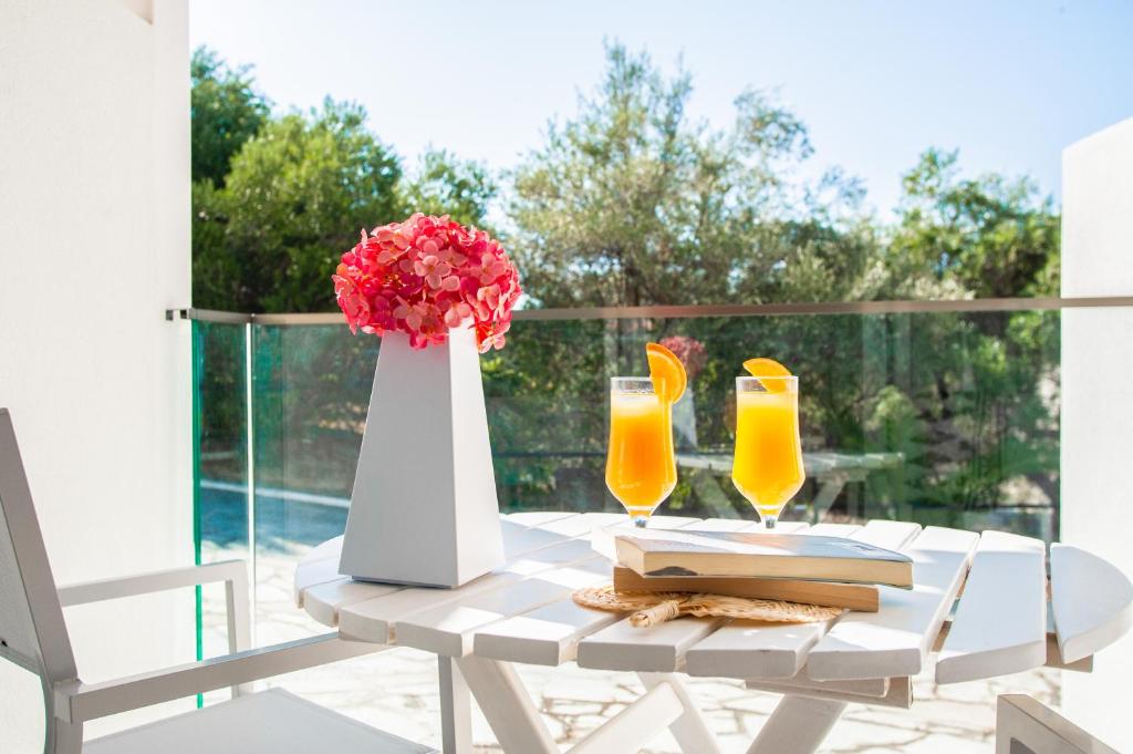 Saulaina terase ar divām dzērienu glāzēm un ziedu kompozīciju. Ideāla vieta relaksācijai ar grāmatu un mierīgu skatu uz dabu.