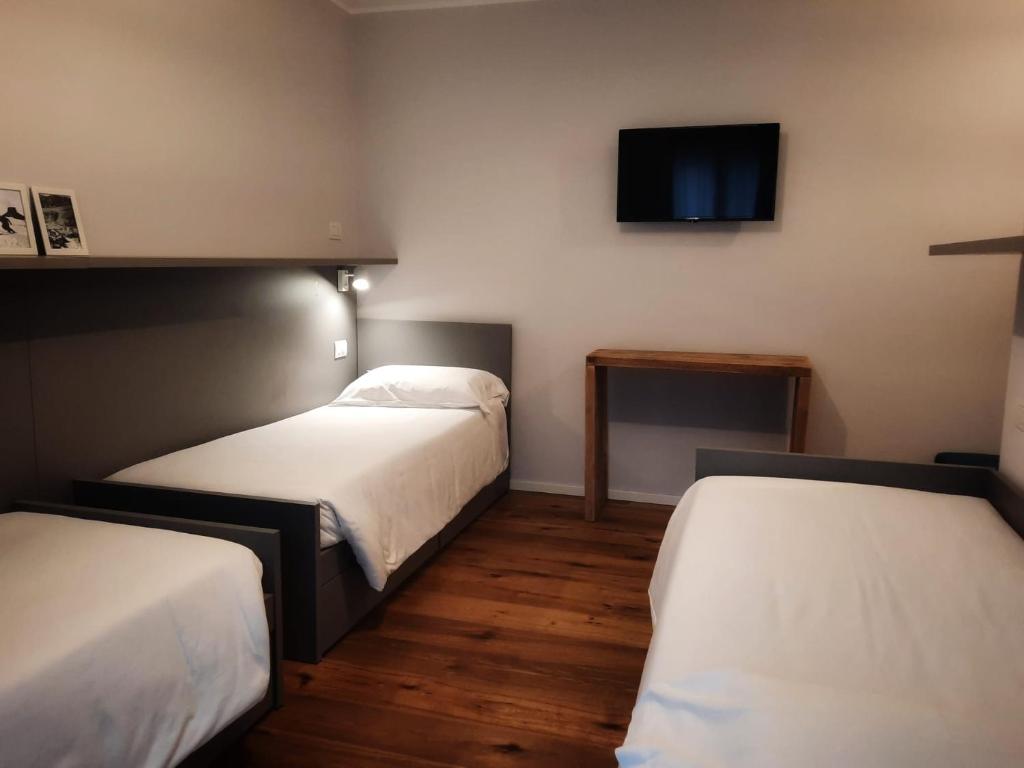 Mūsdienīgs viesnīcas numurs ar divām gultām, koka grīdu un televizoru pie sienas. Gaismas un vienkāršs interjers rada patīkamu atmosfēru.