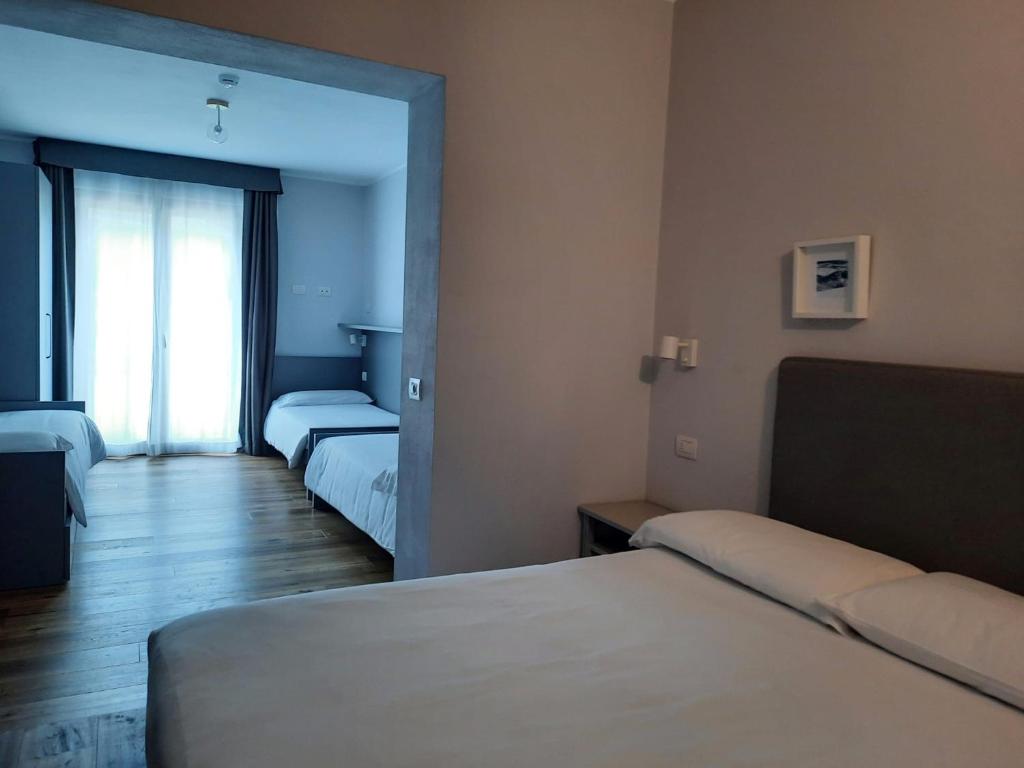 Mūsdienīgs viesnīcas numurs ar divām gultām un logu, kas ved uz ārpusi, nodrošinot dabisko apgaismojumu. Interjers ir vienkāršs un elegants, ar koka grīdu un neitrālām krāsām.