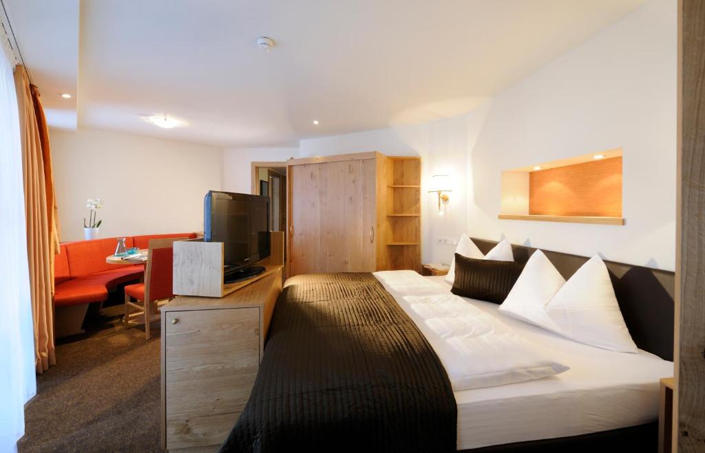 Mūsdienīga viesnīcas istaba ar plašu gultu, televizoru un ērtu atpūtas zonu. Istaba ir iekārtota ar siltām krāsām un koka mēbelēm, radot mājīgu atmosfēru.