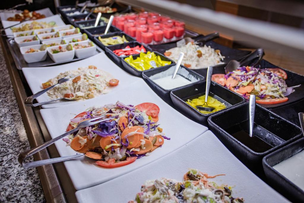 Bagātīgs salātu bārs ar dažādām uzkodām, salātiem un desertiem. Krāsaini dārzeņi un mērces piedāvā plašu izvēli veselīgiem ēdieniem.