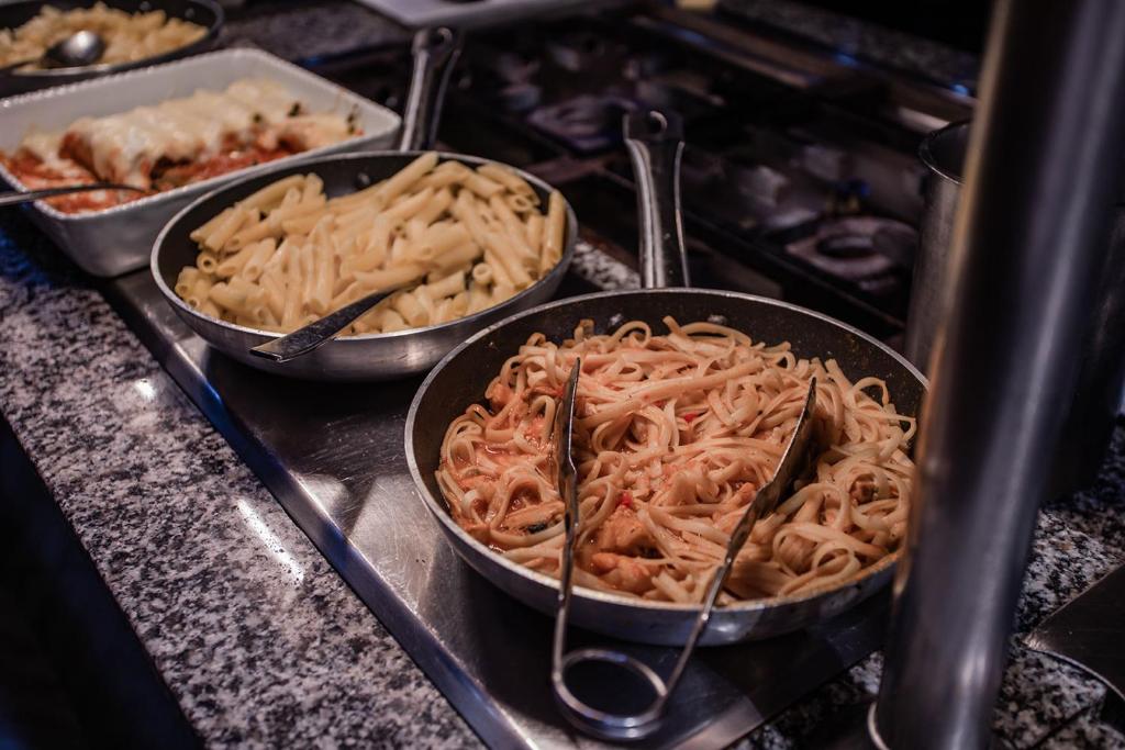 Dažādas makaronu šķirnes, tostarp spageti un penne, pasniegtas uz galda. Šī ir lieliska izvēle itāļu virtuves cienītājiem.