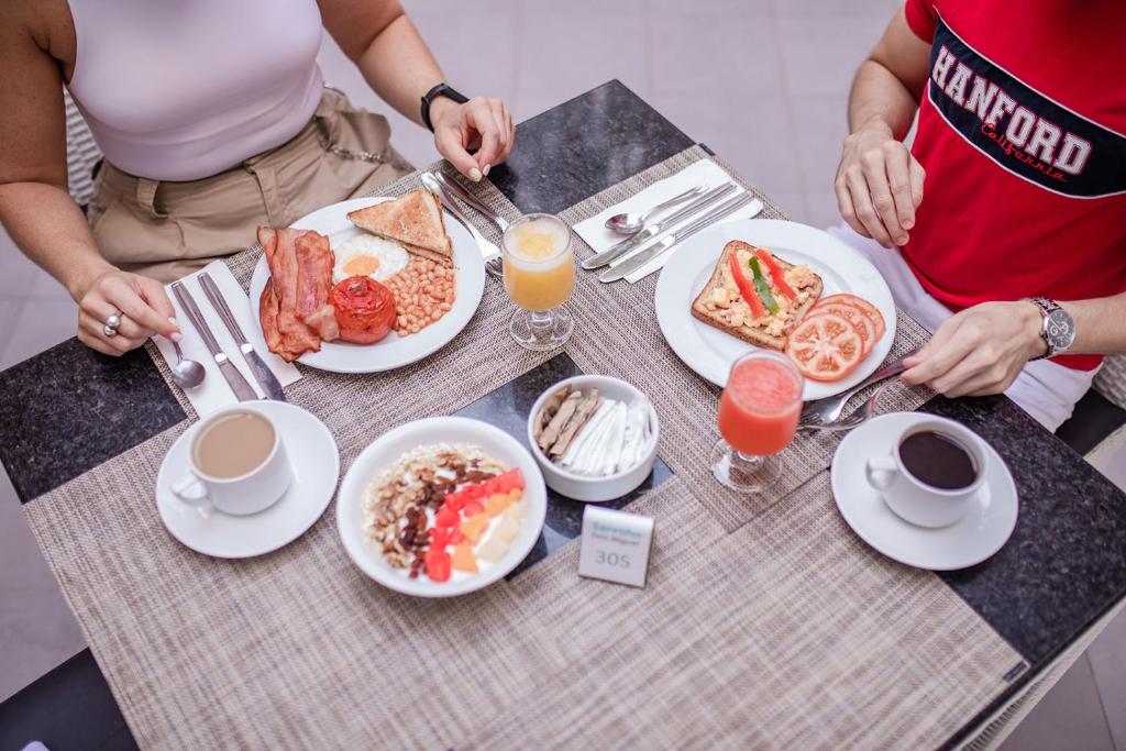 Brokastu galds ar dažādām ēdienu izvēlēm, tostarp olu, bekonu, grauzdiņiem un salātiem, kā arī dzērieniem, piemēram, kafiju un sulām. Ideāla atmosfēra relaksējošām brokastīm.