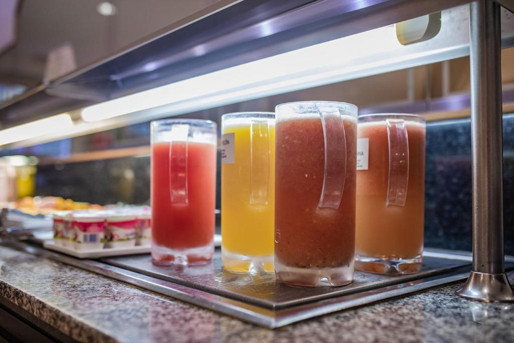 Svaigu dzērienu stends ar dažādiem kokteiļiem un sulām, kas pasniegti caurspīdīgās krūzēs. Ideāli piemērots brokastu vai bufetes atmosfērai.