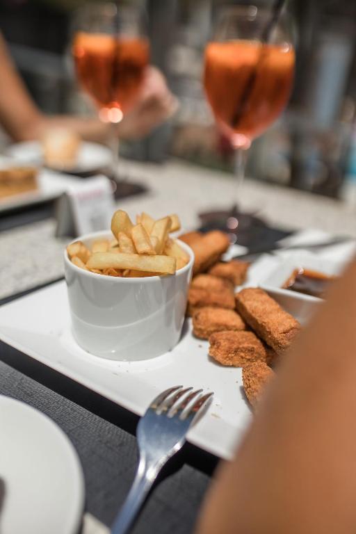 Ceļojumu galda klāšana ar kraukšķīgām frī kartupeļiem un gaļas uzkodu, blakus redzami divi dzērieni.