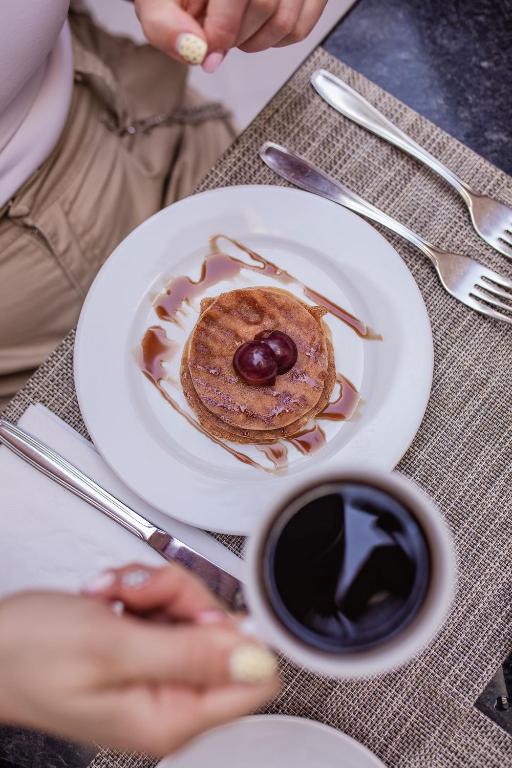 Gards pankūku deserts ar šokolādes mērci un vīnogu, blakus karsta kafija.
