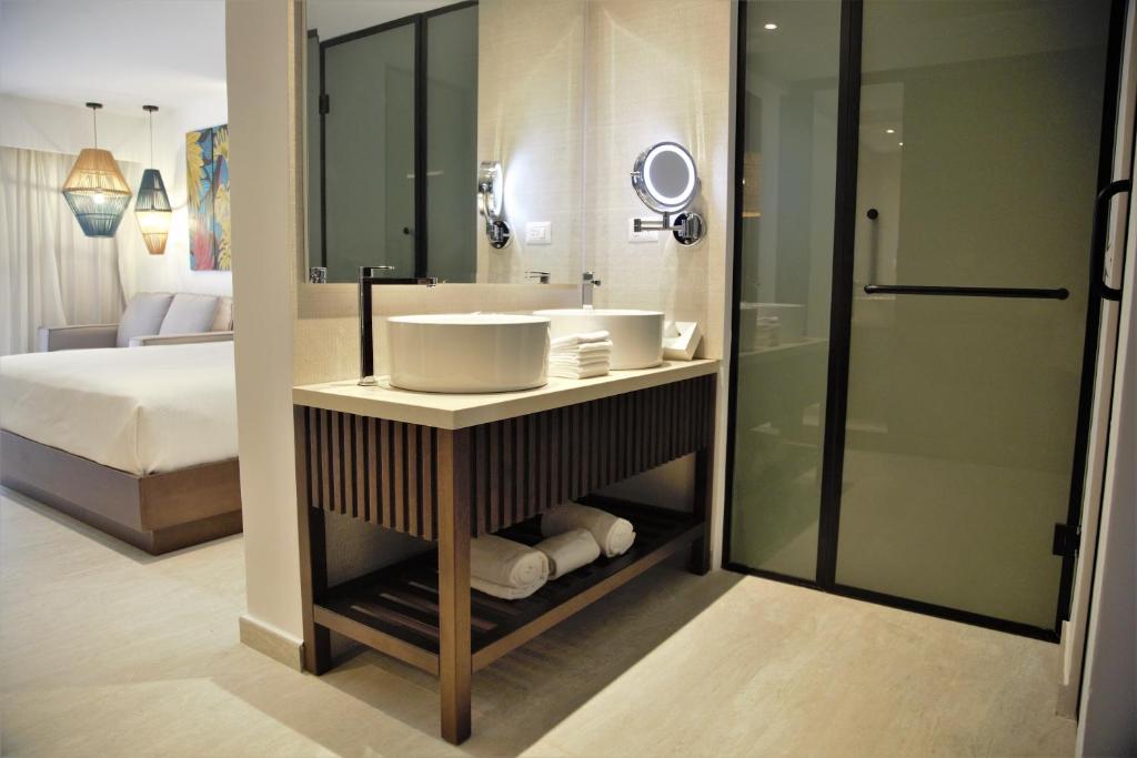 Mūsdienīga vannas istaba ar elegantu izskatu, tajā ir moderna izlietne un dušas kabīne, kā arī viesistabas skats.