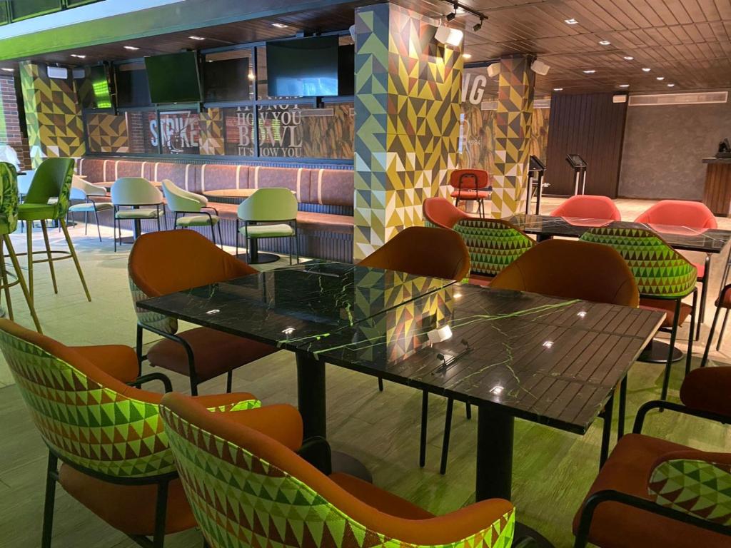 Mūsdienīga bāra iekārtojums ar krāsainām krēslām un ģeometriskām sienām. Ideāla vieta atpūtai un socializēšanai.