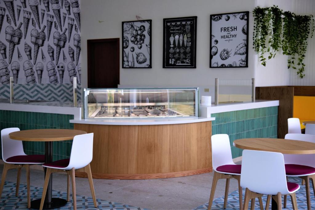 Mūsdienīgs saldējuma veikals ar ērtiem galdiem un krēslu komplektiem, dekorēts ar krāsainu flīžu grīdu un stilīgu, augļu tematikas interjeru. Saldējuma vitrīna ir centrālā uzmanība, un telpu rotā augu dekorācijas.