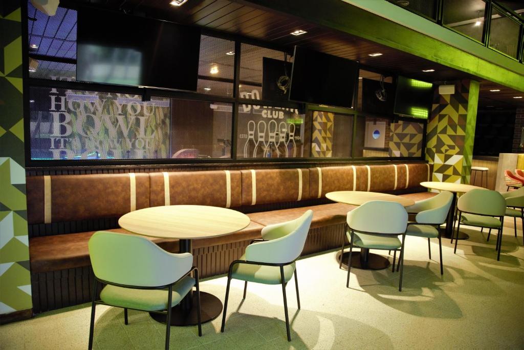 Mūsdienīgs bārs ar komfortablām sēdvietām un elegantu interjeru, kas piedāvā relaksējošu atmosfēru. Interjerā ir redzami televizori un ģeometriski dekori.