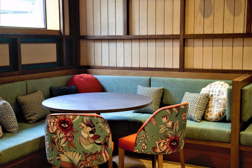 Mūsdienīgs un ērts interjers ar dīvānu un krēsliem ar ziedu rakstiem, kā arī apaļu galdu, kas veido patīkamu atpūtas stūri.