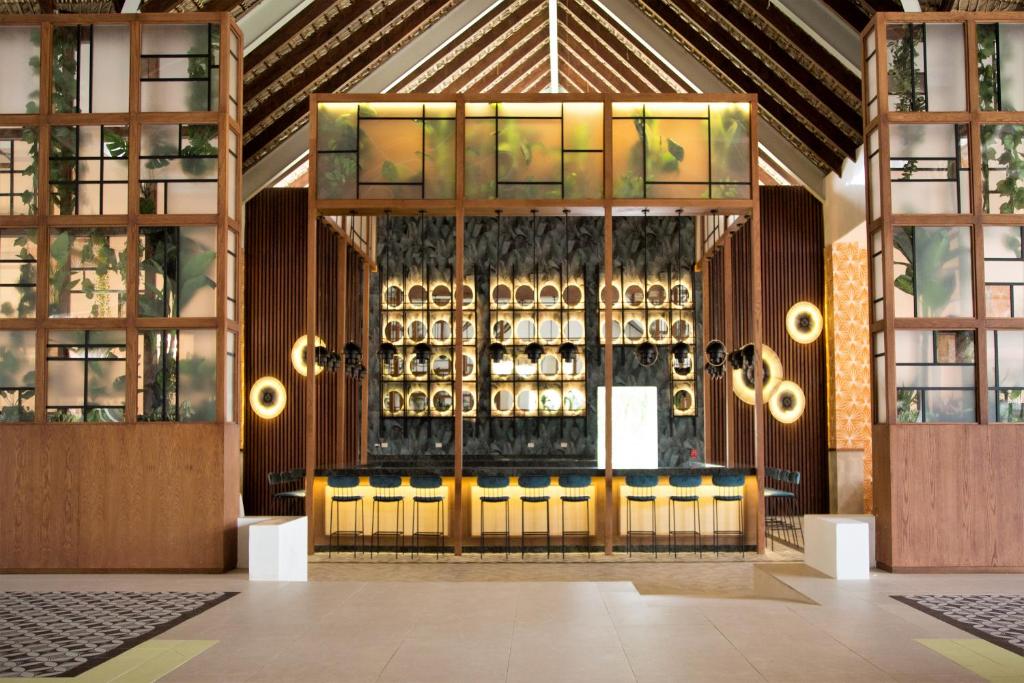 Mūsdienīgs bārs ar koka elementiem un augu dekorācijām, kas veido elegantu atmosfēru. Interjers apvieno dabu un mūsdienīgu dizainu, radot relaksējošu vidi.