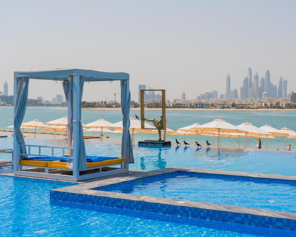 Vasaras atpūtas vieta ar baseinu un pludmales gultām, fons ar modernām pilsētas ēkām Dubaijā. Ideāla vieta relaksācijai un atpūtai.