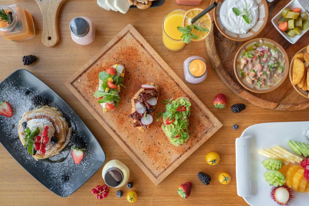 Paplāte ar dažādiem gardumiem, tostarp pankūkām ar augļiem, avokado tostermaizi un salātiem, kā arī dzērieniem un desertiem. Krāsaini ēdieni un dzērieni rada viesmīlīgu un svinīgu atmosfēru.