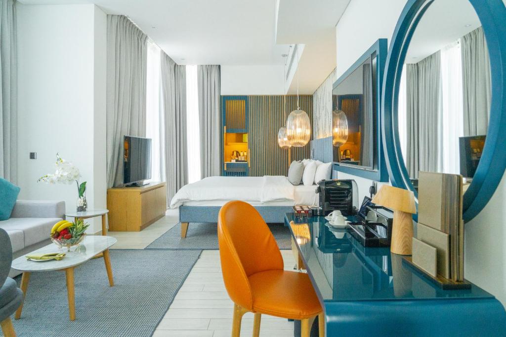 Mūsdienīgs viesnīcas numurs ar elegantu interjeru, kurā ir gaismas elementu un dekoratīvu akcentu kombinācija, kā arī ērta atpūtas zona un darba galds.