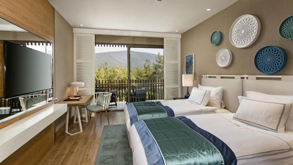 Moderns numurs Titanic Luxury Collection Bodrum ar balkonu un skatu uz kalniem.