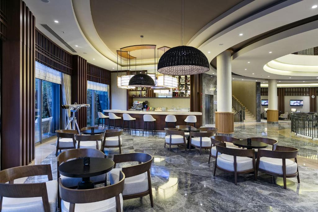 Mūsdienīgs bārs Titanic Luxury Collection Bodrum ar elegantiem krēsliem un apgaismojumu.