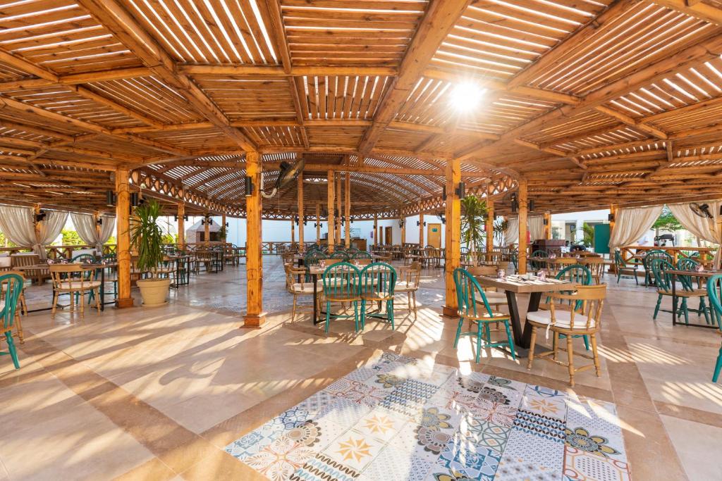 Koka konstrukcijas restorāna telpa ar saulainu gaismu, dekorēta ar zaļiem krēsliem un ainavu, kas veido relaksējošu atmosfēru.