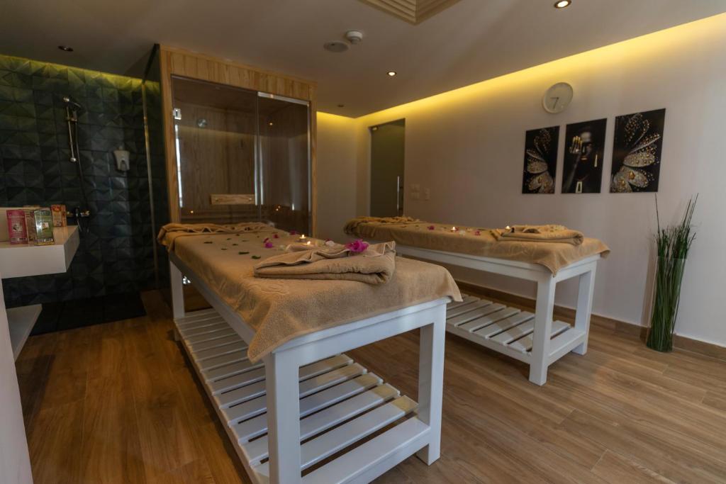 Mūsdienīgs spa telpa ar divām masāžas galdiem, dekorētiem ar ziedlapiņām, un dušu fonā, radot relaksējošu atmosfēru. Gaisma un dizains veicina mierīgu un atjaunojošu pieredzi.