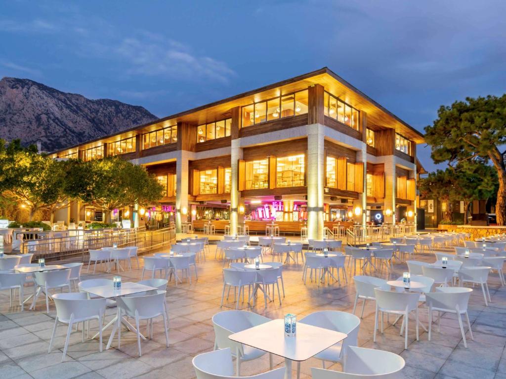 Rixos Sungate - Āra restorāns ar baltiem galdiem piekrastē, vakarā