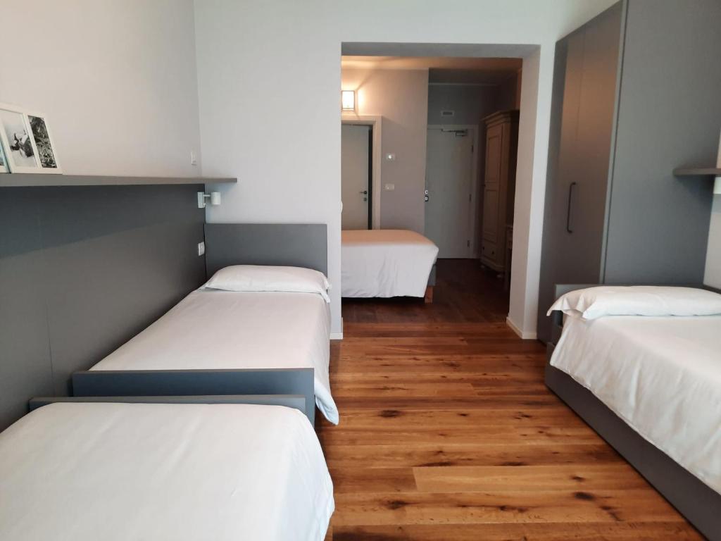 Mūsdienīga guļamistaba ar trim gultām un koka grīdu, kas rada siltu atmosfēru. Interjerā ir pelēki toņi un minimālistiskas mēbeles, kas nodrošina komfortu un eleganci.