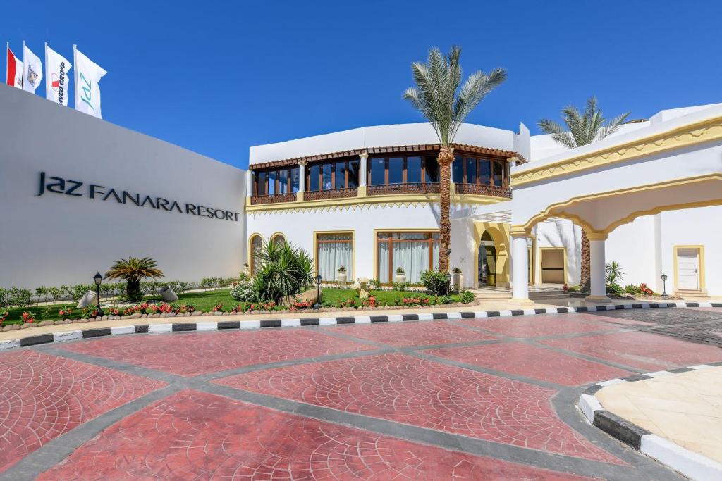 Jaz Fanara Resort ieeja ar palmām un ziedu dārzu, skaidrā zilā debesīs. Ideāla vieta atpūtai un relaksācijai.