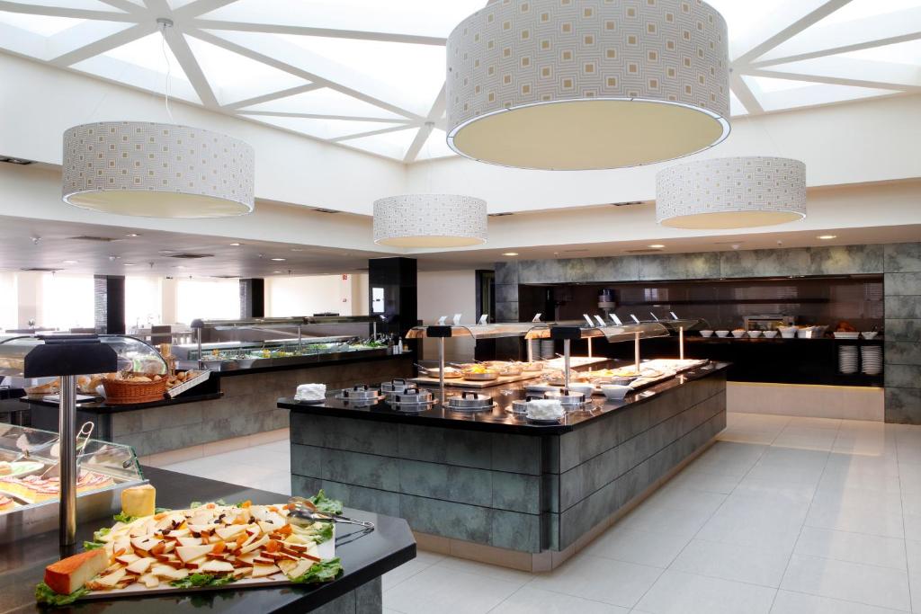 Mūsdienīgs bufetes restorāns ar elegantu apgaismojumu un plašu ēdienu izvēli, kas pasniegta uz melna akmens galda. Gaismas elementi un mūsdienīga arhitektūra rada patīkamu atmosfēru.