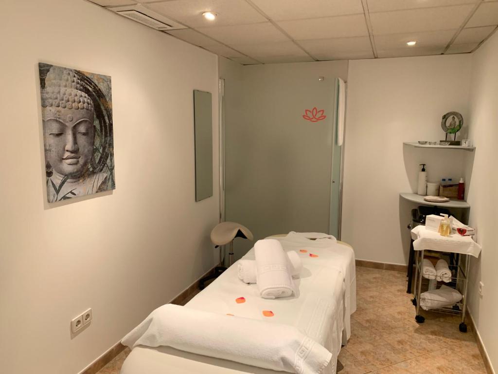 Mierīgas masāžas telpas interjers ar Budas attēlu uz sienas, masāžas galdu un relaksējošu atmosfēru. Ideāla vieta atpūtai un labsajūtai.