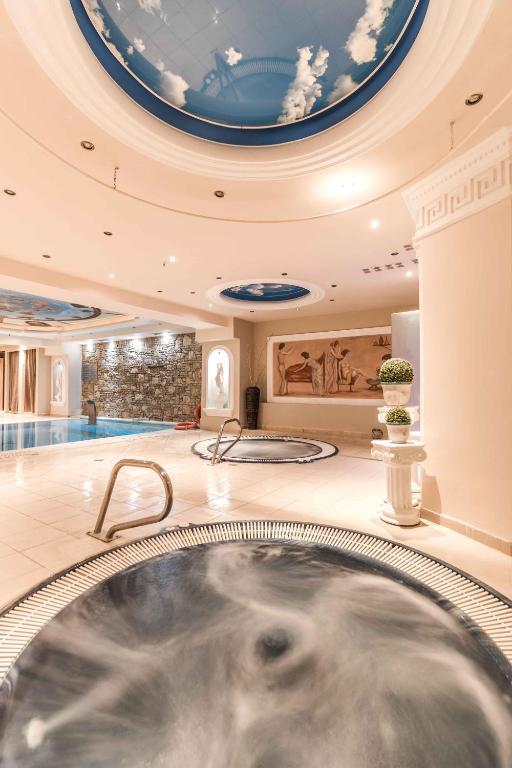 Luksusa spa telpa ar apaļām burbuļvannām un baseinu, zilām debesīm uz griestiem un elegantiem dekoratīviem elementiem. Ideāla vieta relaksācijai un atpūtai.