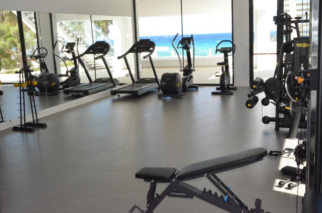 Mūsdienīga trenažieru zāle ar skatu uz jūru, kurā redzami dažādi fitnesa aprīkojumi, piemēram, skrejceliņi un svaru trenažieri. Gaismas un plašuma sajūta rada patīkamu treniņu atmosfēru.
