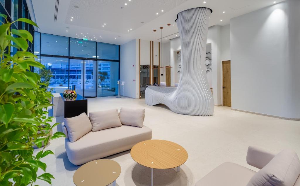 Mūsdienīgs un stilīgs viesnīcas reģistratūras interjers ar unikālu dizaina stabu, plašām logu vitrīnām un ērtām mēbelēm. Gaismas un augi piešķir telpai dzīvīgumu.