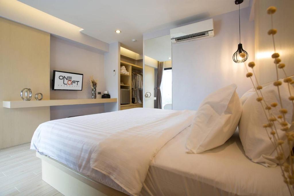 Mūsdienīga guļamistaba ar ērtu gultu, televizoru un stilīgu apgaismojumu. Interjers ir gaišs un vienkāršs, radot relaksējošu atmosfēru.