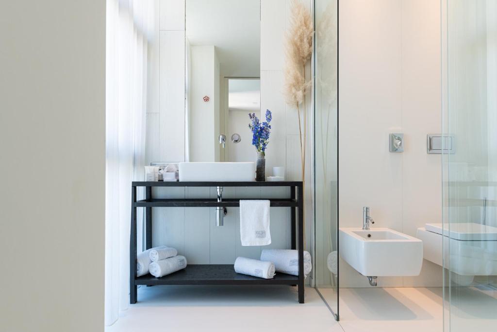 Mūsdienīgs vannas istabas interjers ar elegantu melnu izlietni un stikla dušu, dekorēts ar ziediem un dvieļiem.