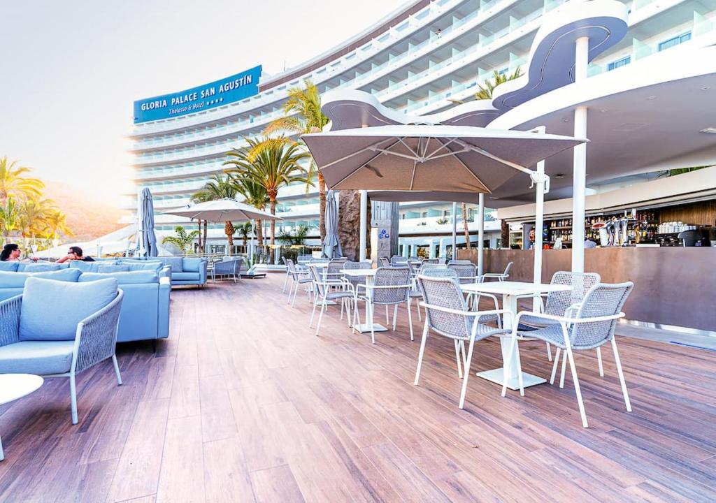 Moderns viesnīcas terases skats ar komfortablām mēbelēm, sauļošanās krēsliem un palmām. Ideāla vieta relaksācijai un atpūtai.