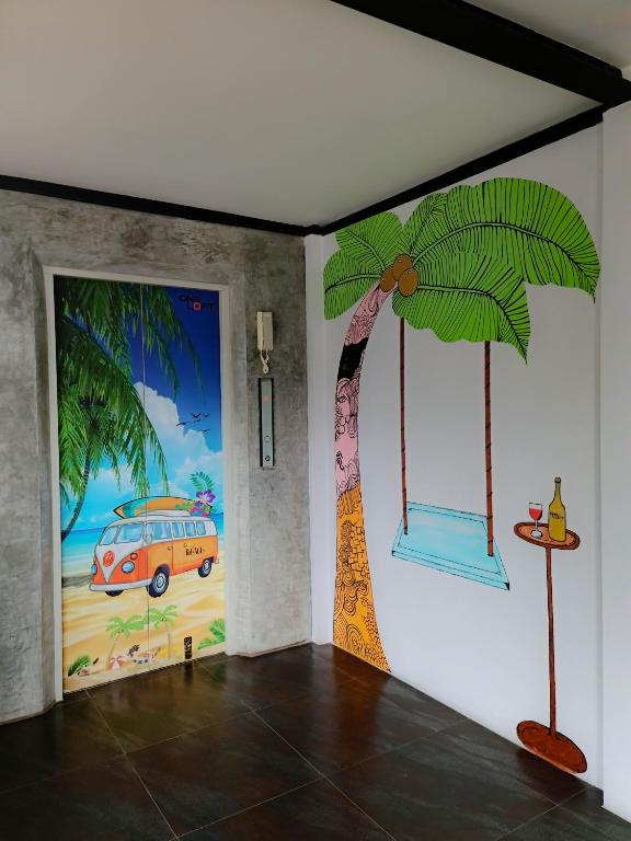 Krāsains interjera elements ar pludmales motīviem, tostarp mākslinieciskas sienu gleznas ar palmu un šūpuli, kas papildina draudzīgu atmosfēru.