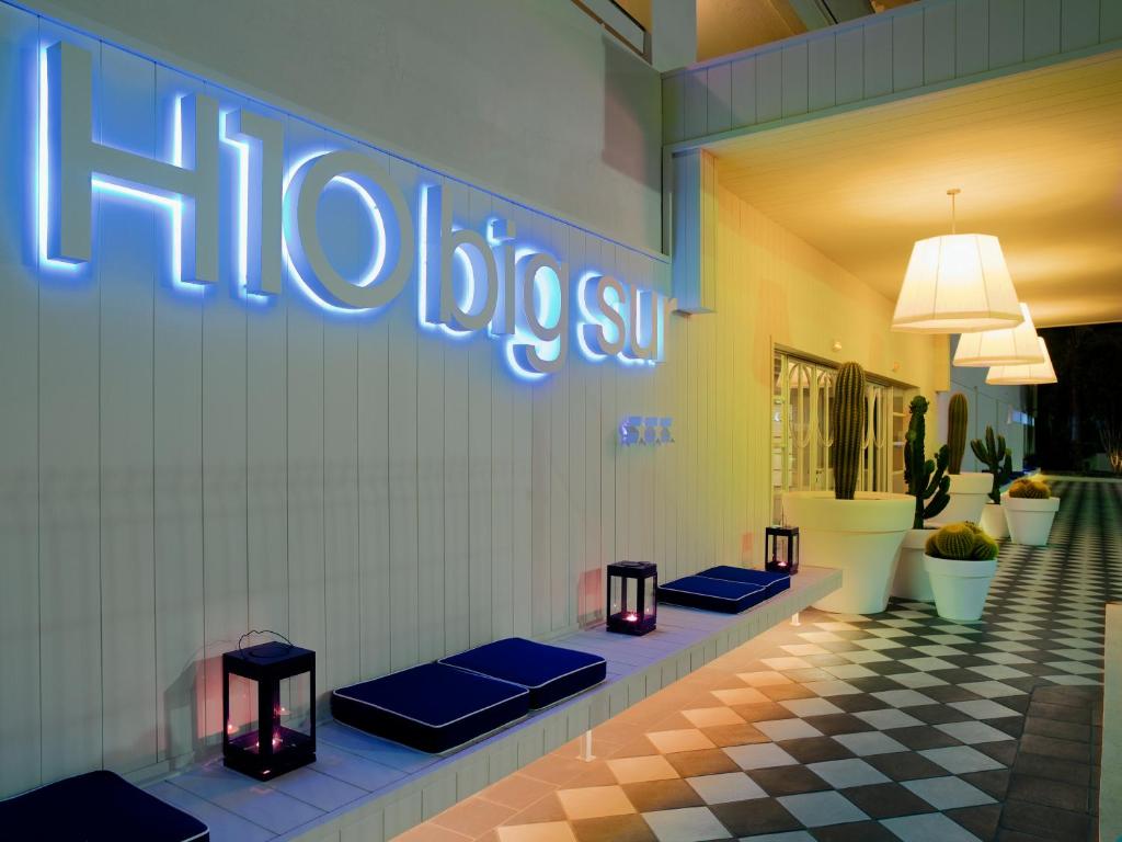H10 Big Sur viesnīcas ieeja ar modernu apgaismojumu, stilīgu dizainu un kaktusu dekorācijām. Eleganti gaismas elementi radīja viesmīlīgu atmosfēru.