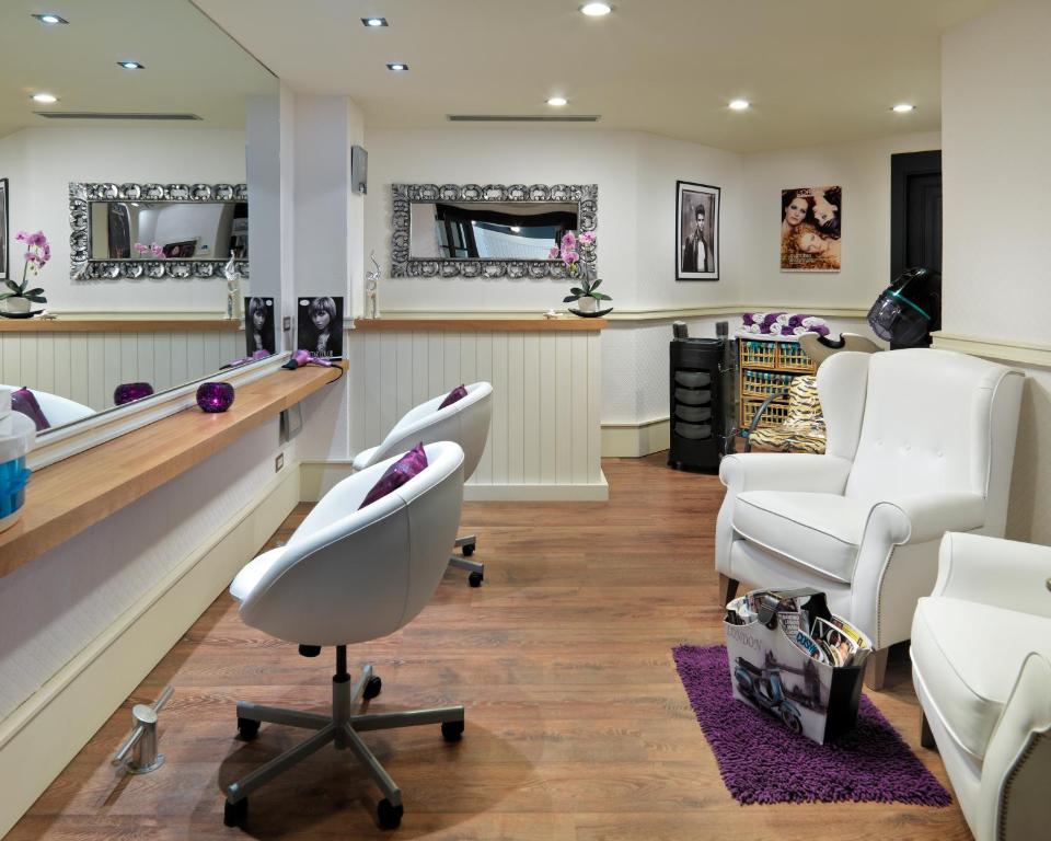 Mūsdienīgs frizieru salons ar elegantiem sēdekļiem, spoguļiem un dekoratīvām orhidejām, radot relaksējošu atmosfēru. Salonā ir arī žurnālu kaste un apgaismojums, kas piešķir siltumu.