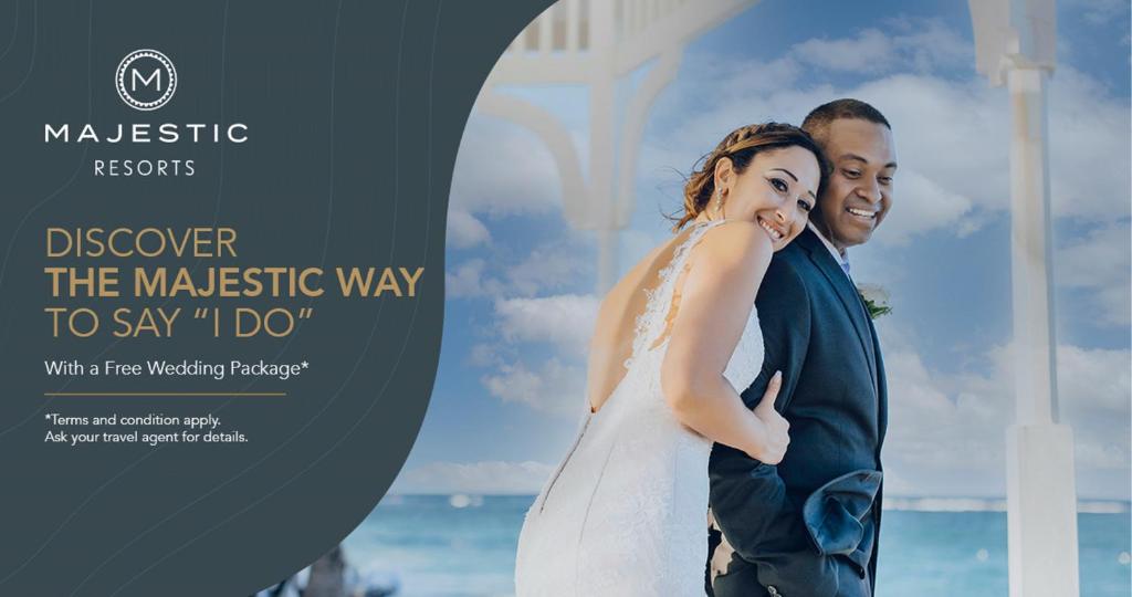 Jaunais pāris laimīgi pozē romantiskā pludmales kāzu vietā, izceļot svinīgumu un mīlestību. Reklāma par brīvu kāzu paketi no Majestic Resorts.