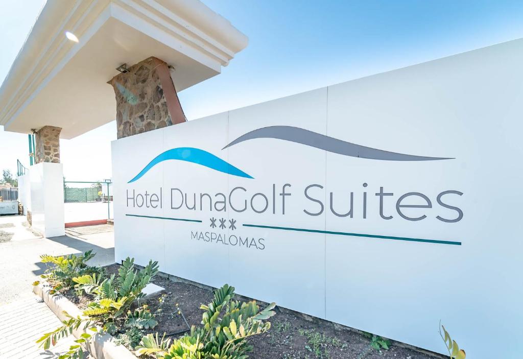 Viesnīcas DunaGolf Suites ieejas zīme Maspalomas, ar modernu dizainu un dabīgu apzaļumošanu. Ideāla vieta atpūtai un izklaidei.