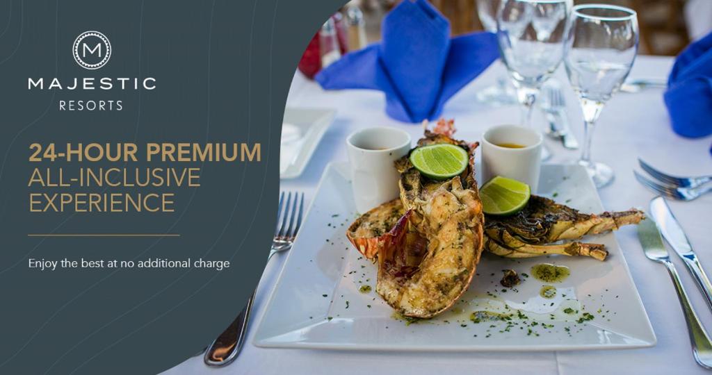 Gourmet ēdiens ar garnelēm un citrona šķēlēm, servēts uz baltā šķīvja, kopā ar dzērieniem un elegantiem galda piederumiem. Ideāls attēls par 24 stundu premium visaptverošu pieredzi Majestic Resorts.