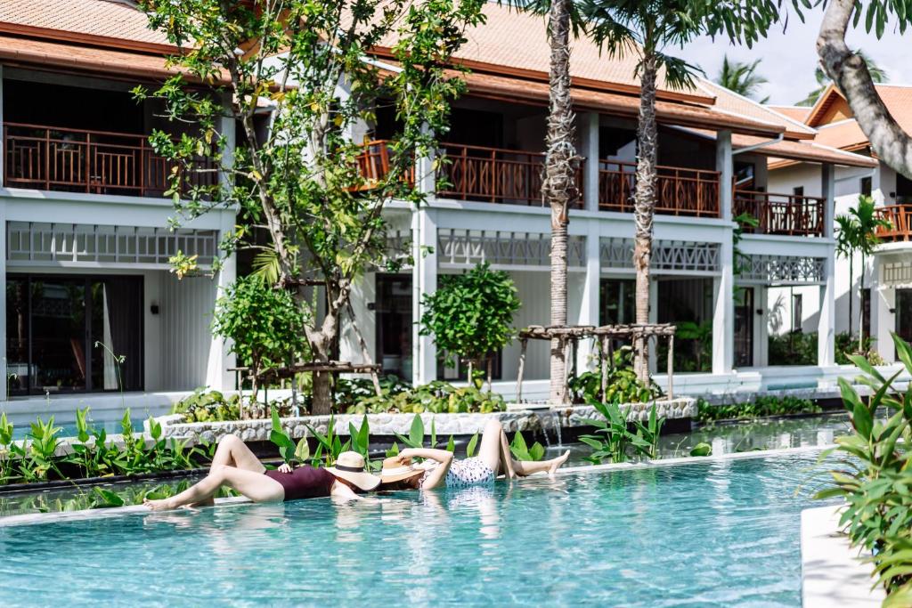 Divas sievietes relaksējas pie baseina Grand Mercure Khao Lak Bangsak.