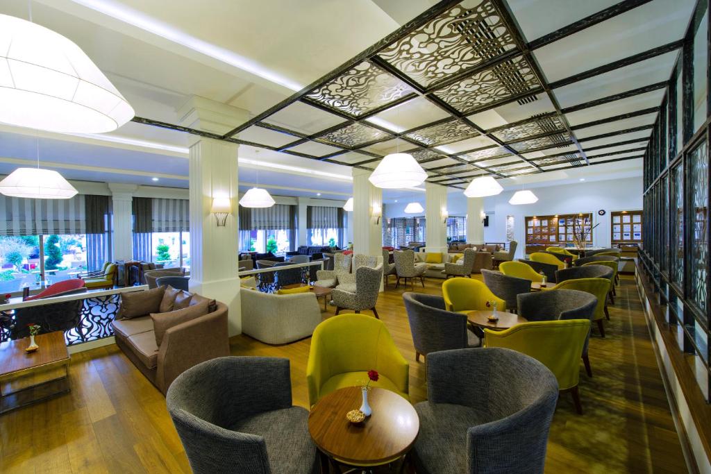 Mūsdienīgs kafejnīcas interjers ar dažādu krāsu krēsliem un sofām, ērtām sēdvietām un gaišu apgaismojumu. Telpa ir plaša un eleganta, nodrošinot patīkamu atmosfēru.