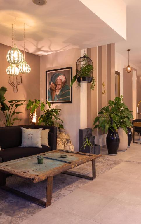 Mūsdienīga viesistaba ar elegantiem gaismas ķermeņiem, zaļām telpaugiem un mākslas darbu uz sienas, radot mierīgu un aicinošu atmosfēru.